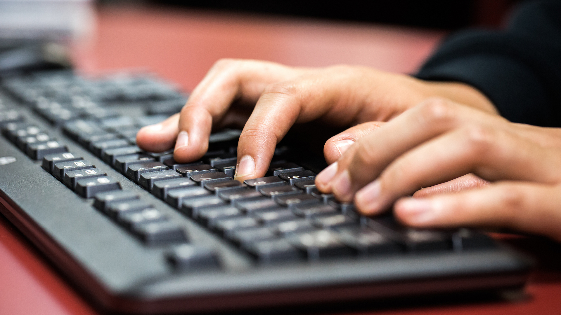 Close up of hands typing on a computer keyboard